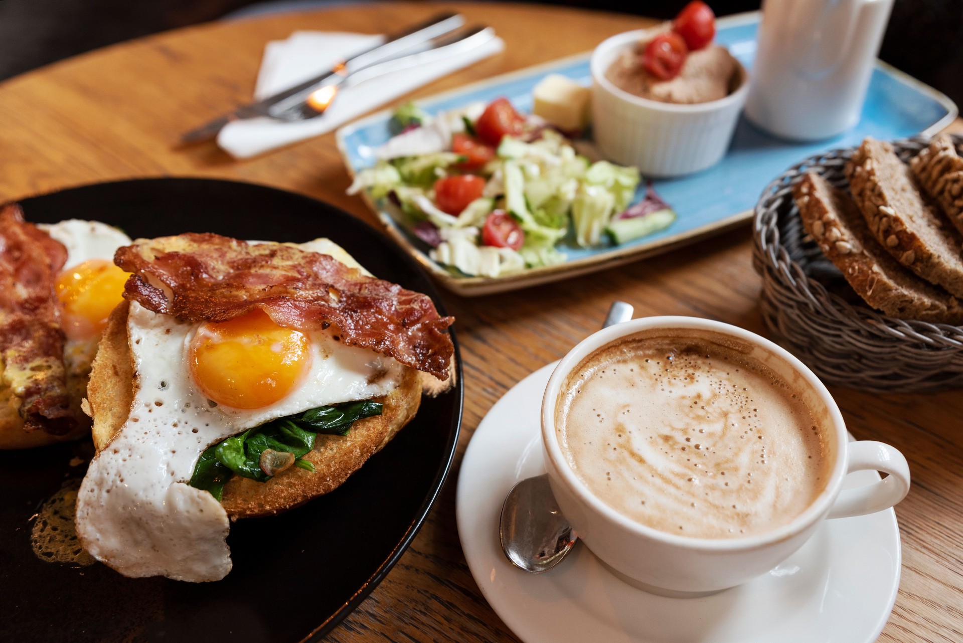 Food and drink ready to eat for breakfast in restaurant. Fried egg on sandwich with cappuccino. Healthy eating.